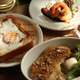 Bread, eggs, bacon, fish, and other food are placed in bowls on a table.